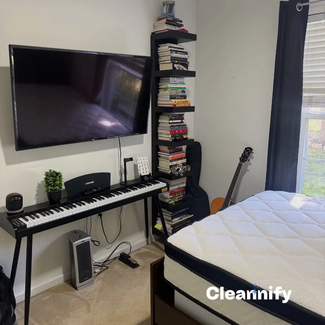 After bedroom cleaning in Charlotte showing a cleaned TV wall, keyboard area, and made bed